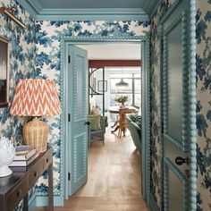 the hallway is decorated with blue and white wallpaper, along with a lamp on a table