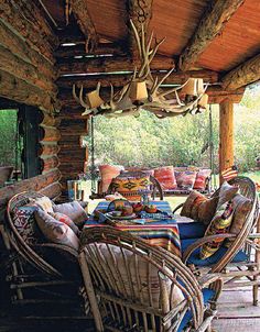 an outdoor covered porch with wicker furniture and deer antlers hanging from the ceiling