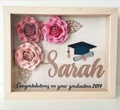 a wooden frame with some flowers and a graduation cap