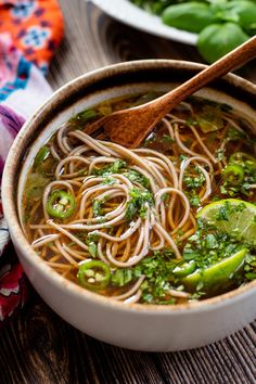 a bowl of noodle soup with chopsticks on the table next to it