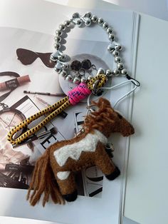 a brown and white horse keychain sitting on top of a table next to a magazine