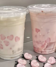 two plastic cups filled with ice cream and candy hearts next to each other on a table