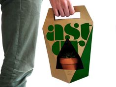 a person holding a box with a plant in it and the packaging is printed on