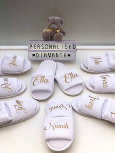 white slippers with personalized names on them and a teddy bear next to them