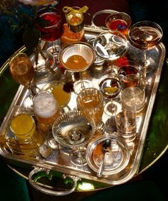 a tray filled with different types of glasses on top of a green tableclothed surface