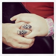 two hands holding each other with rings on their fingers and tattoos on their thumbnails