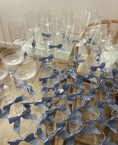 many wine glasses with blue bows on them are sitting on a table next to each other