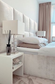 a white bed sitting next to a night stand with a lamp on top of it