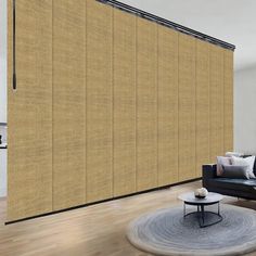 a living room with a couch, coffee table and large window covered in beige blinds