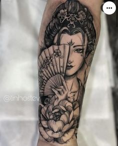 a person with a tattoo on their arm holding a fan and flowers in front of them