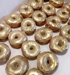 there are many doughnuts that have been placed on the white tablecloth with gold frosting