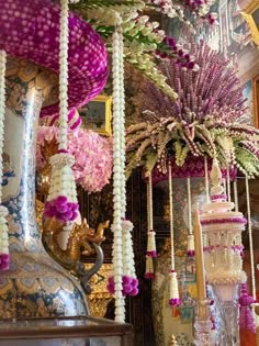 an assortment of vases and flowers are hanging from the ceiling in a room with ornate wallpaper