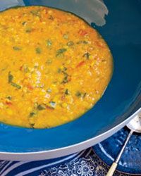 a blue bowl filled with yellow food on top of a table next to utensils