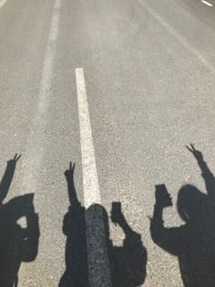 three people standing in the middle of a road with their hands up and arms raised