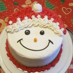 a white cake with red frosting and decorations on it's face, sitting on a plate