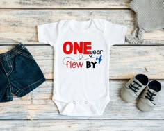 one year new baby onesuit and shoes on a wooden background with the word,'one year flew by '