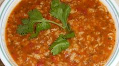 a white bowl filled with soup and garnished with cilantro leaves on top