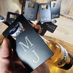 a person holding up a bottle opener with the initials j and j on it in front of some bottles