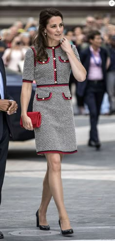 a woman in a black and white dress walking down the street while talking on her cell phone