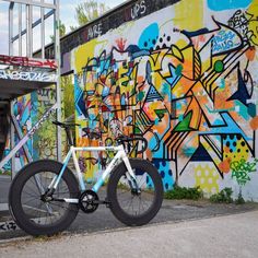 a bicycle parked in front of a graffiti covered wall