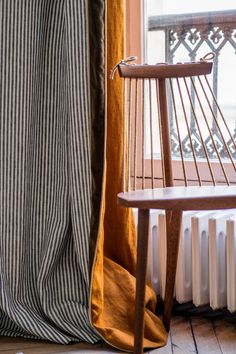 a chair sitting in front of a window next to a wooden table and radiator