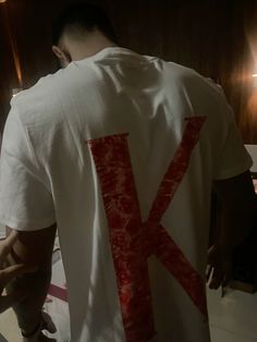 a man wearing a white shirt with the letter k painted on it's back