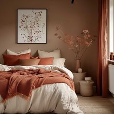 a bed with orange and white pillows in a bedroom next to a painting on the wall