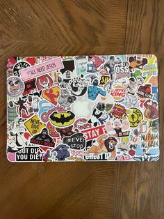 a laptop covered in lots of stickers on top of a wooden table