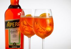 an advertisement for aperol spritz with two glasses filled with liquid and orange slices