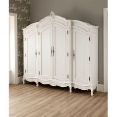 an ornate white armoire in a room with wood floors and wall paper on the walls