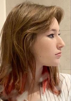 a woman is brushing her teeth in front of a mirror with red streaks on it