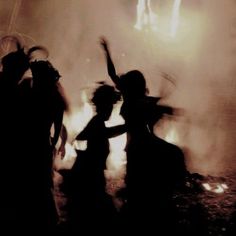 two children are dancing in front of a fire with their arms up and hands out