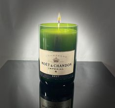 a lit candle sitting on top of a table next to a bottle of wine in front of a white background