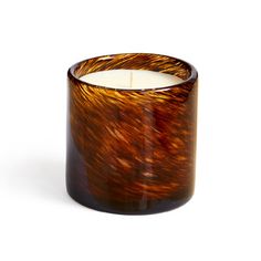 a candle that is sitting in front of a white background with an orange and brown design on it