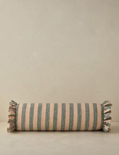 a striped pillow sitting on top of a white table next to a vase and potted plant