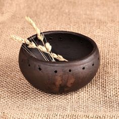 a brown bowl with two stalks of wheat in it