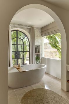 a large white bath tub sitting in a bathroom next to a window with an arched doorway