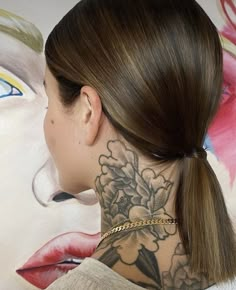 a woman with a tattoo on her neck and behind her ear, looking at a painting