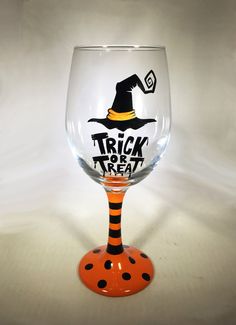 a wine glass with a trick or treat painted on the side and a witch's hat