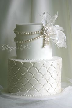 a three tiered white wedding cake with pearls