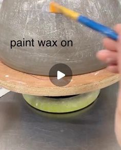 a person is painting a ball on top of a metal object with paintbrushes