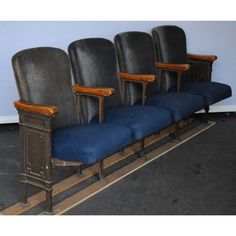 four chairs are lined up in a row with blue seats on each side and one has a wooden armrest