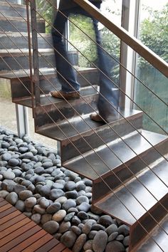 a person walking up some stairs with rocks on the ground and wood handrails