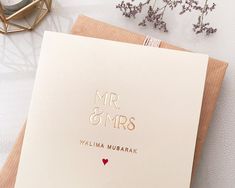 a card with the words mr and mrs written in gold on it next to some flowers