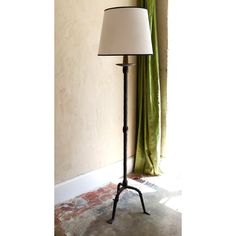 a lamp that is on top of a table next to a window with green curtains