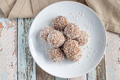 a white plate topped with powdered sugar covered donuts on top of a wooden table