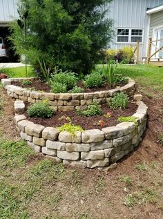 a garden bed made out of rocks and mulchs in front of a house