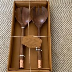 two wooden utensils in a box on the floor