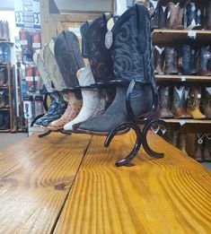 several pairs of cowboy boots are stacked on a shelf in a shoe store with shelves full of shoes