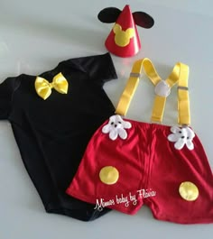 two mickey mouse outfits are shown on a white surface with a red hat and yellow bow tie